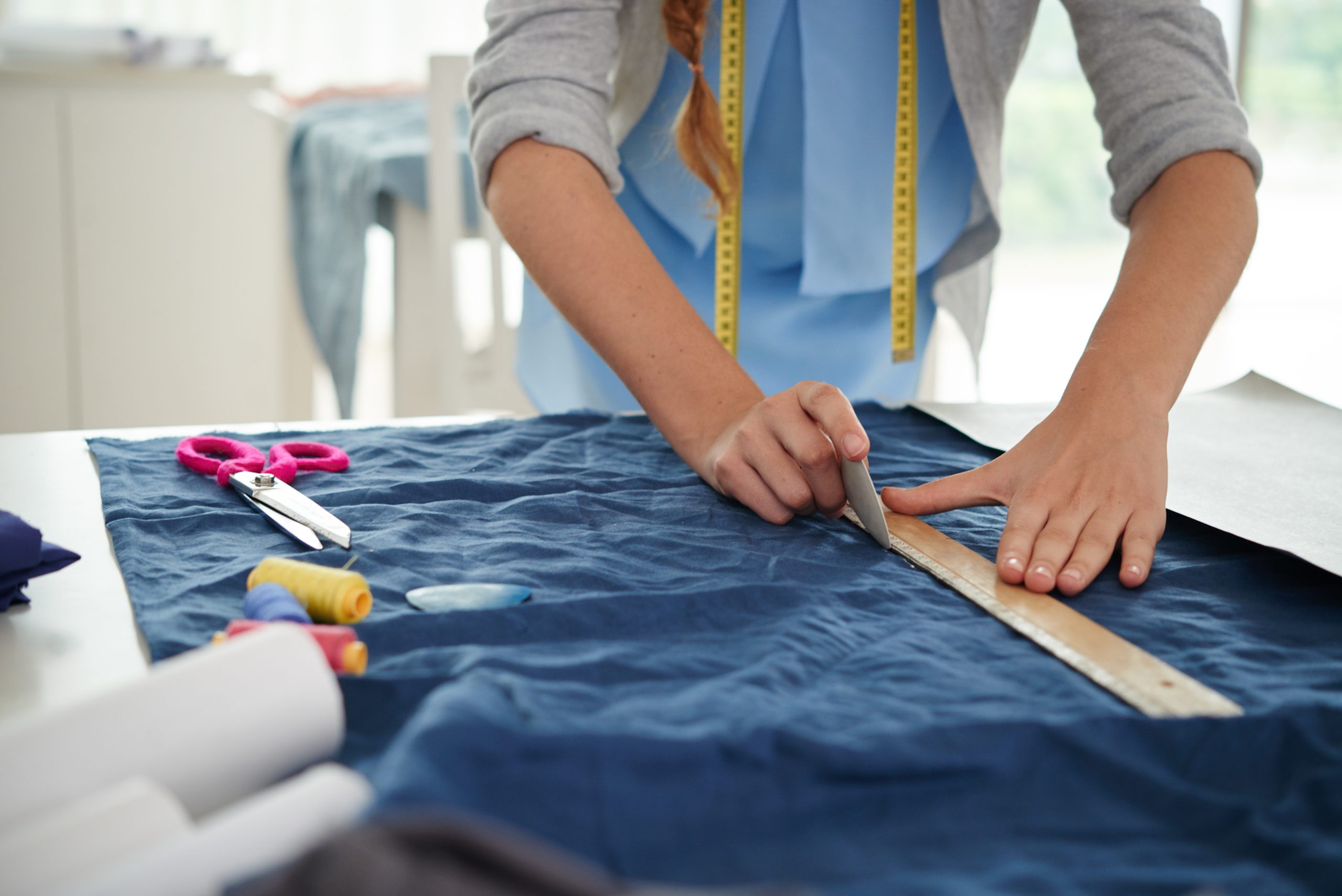 Hands of tailor drawing on fabric before sewing